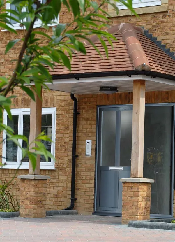 Grey aluminium front door with side glazing on a brick porch