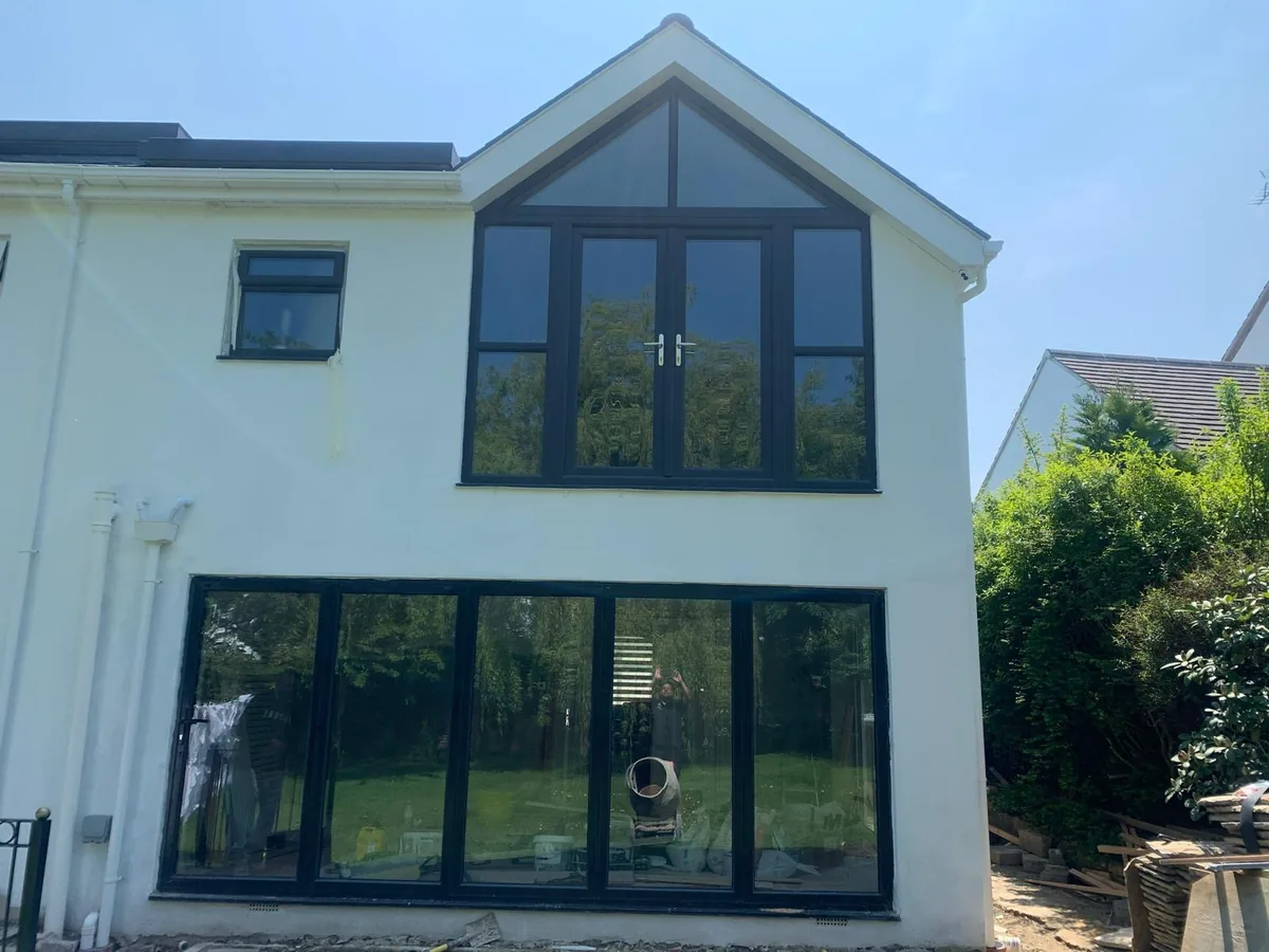 White rendered extension in Hale Barns with five-leaf aluminium bifold doors and aluminium French doors with an apex window above