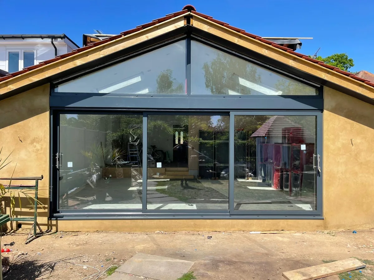 Anthracite grey aluminium triple-track sliding patio door with an aluminium apex window above in Sale